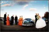photo of a bridal party in front of two cars